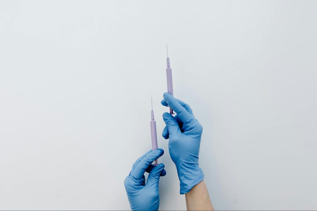 Ръце с медицински ръкавици, които държат спринцовки