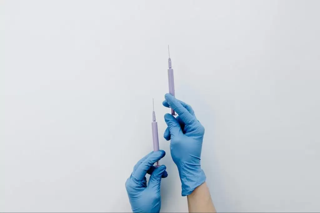 Ръце с медицински ръкавици, които държат спринцовки