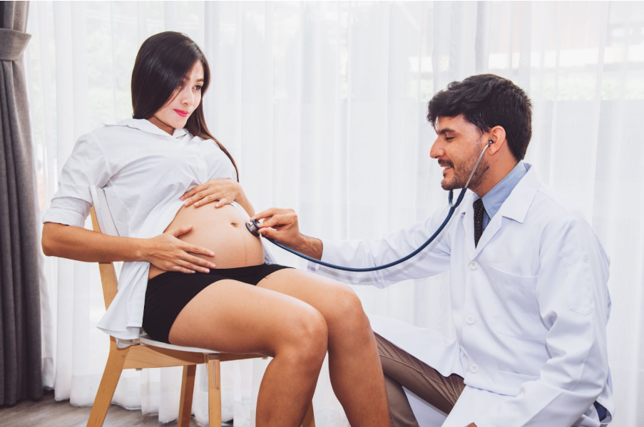 Лекар преглежда бременна жена със стетоскоп, като слуша тоновете на бебето.
