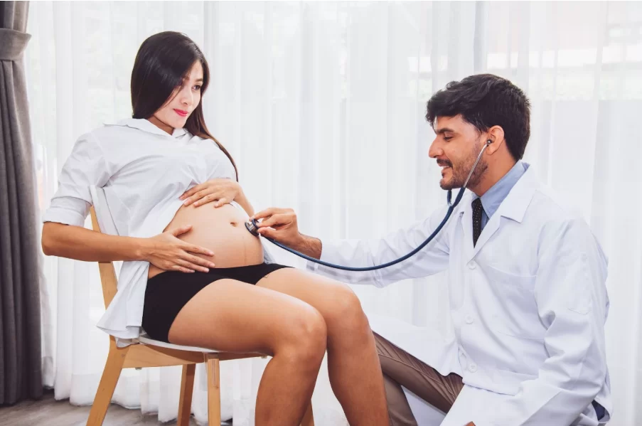Лекар преглежда бременна жена със стетоскоп, като слуша тоновете на бебето.