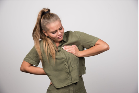 Млада жена е сложила ръка върху гърдата си и лицето е свито от болка.