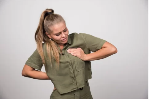 Млада жена е сложила ръка върху гърдата си и лицето е свито от болка.