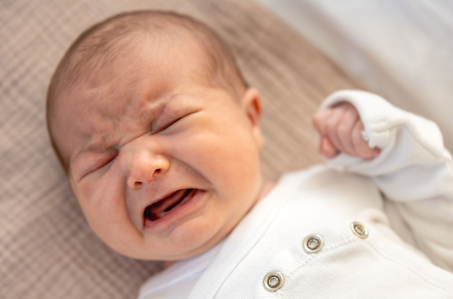 Новородено бебе плаче, сбърчило чело.
